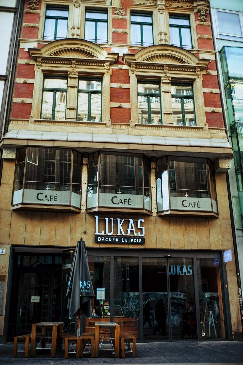 Exterior view of LUKAS Bäcker Leipzig building facade with cafe windows.