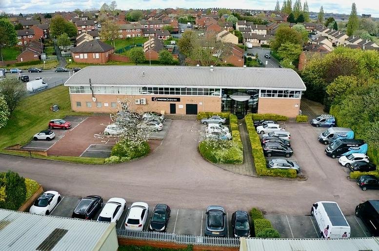 Elevated wide-angle view of the building exterior, parking lot, and surrounding neighborhood.