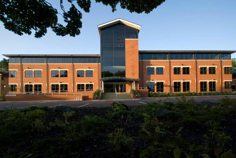 Exterior view of the brick-and-glass facade of the Plas Eirias Business Centre under a clear sky.