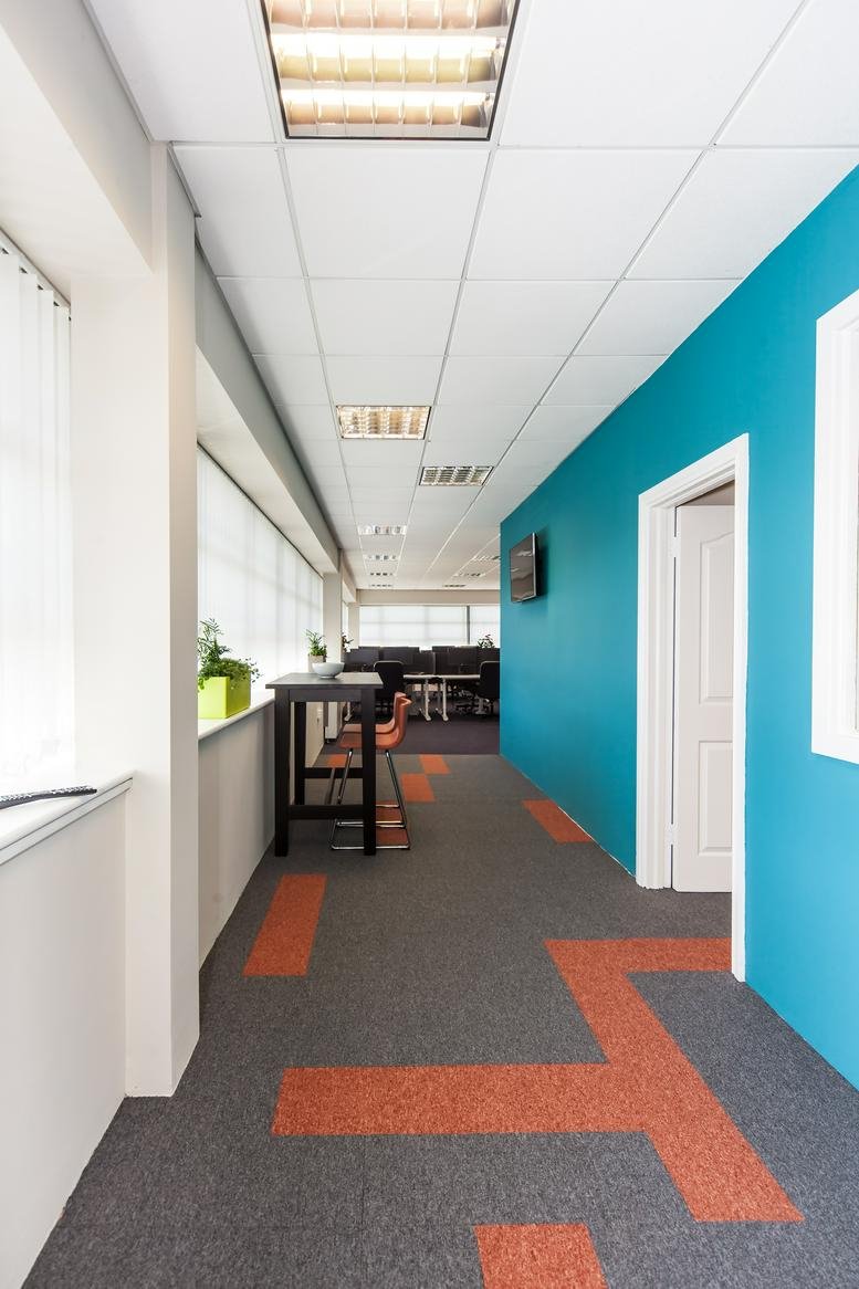 Spacious corridor at Plato Business Park, Damastown Road, with blue feature walls and orange carpet accents.