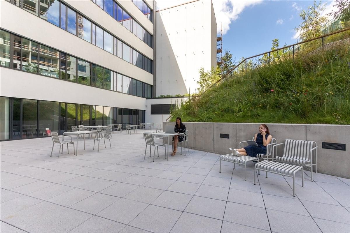 Spacious outdoor terrace at Plzenska 3350/18 with modern seating and a grassy hillside.