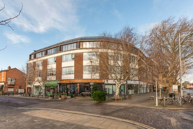 Daytime exterior view of the multi-story curved brick building and storefronts.