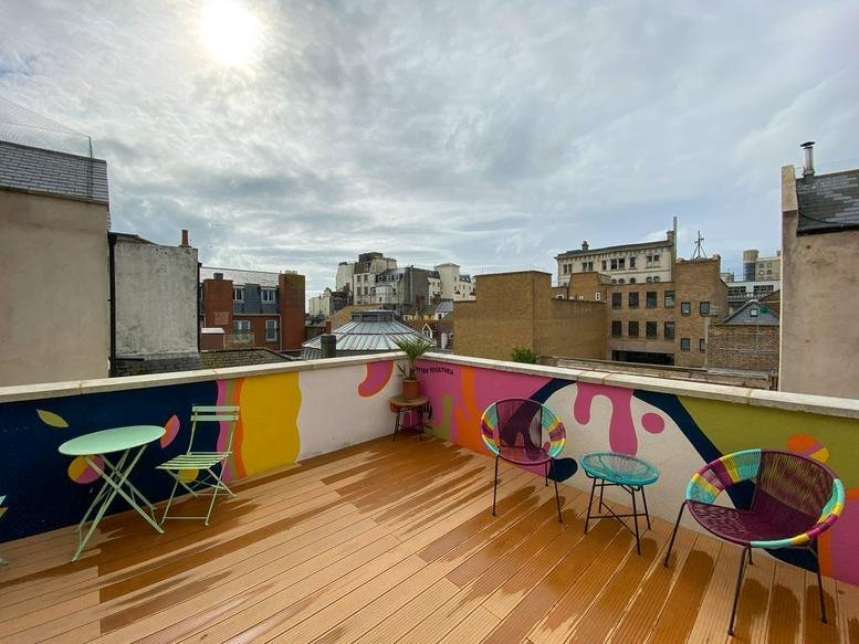 Colorful rooftop terrace with wooden decking and vibrant mural-painted walls.