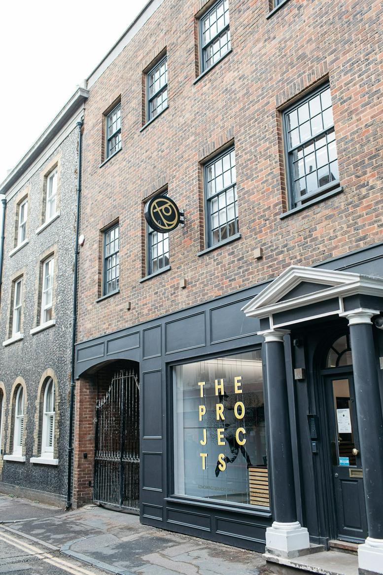 Brick exterior view of the Projects Beach building at 8-9 Ship Street with its dark-framed shopfront.