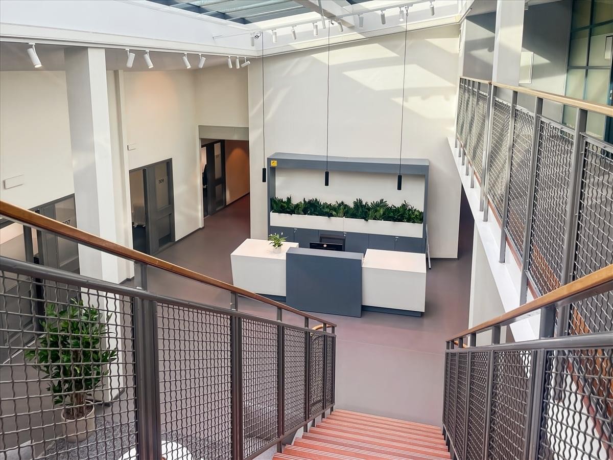 Bright, modern reception area with wooden stairs and a sleek white front desk at Propellervägen 6A, Täby.
