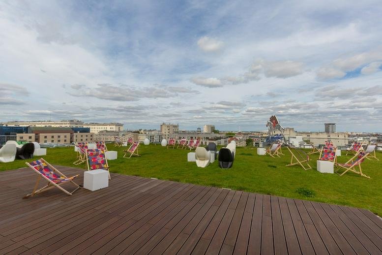 Rooftop terrace at Przeskok 2 Street with artificial grass, lounge chairs, and expansive city views.
