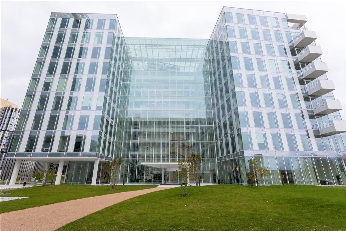 Exterior view of the glass-facade Pujmanove building surrounded by green lawn.