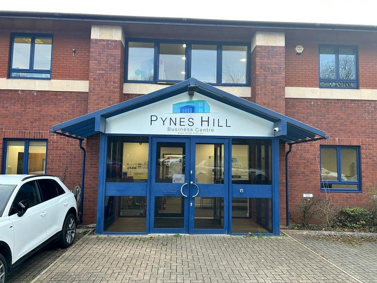Exterior entrance of the brick-built Pynes Hill Business Centre with blue window frames and a peaked canopy.