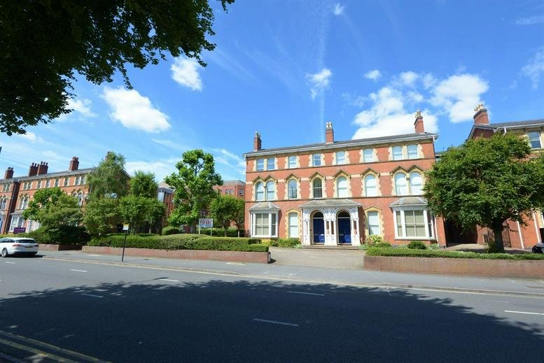 Red brick building facade with white window trim and blue entrance doors.
