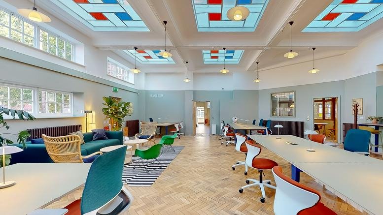 Bright coworking space featuring colorful furniture and stained glass ceiling panels.