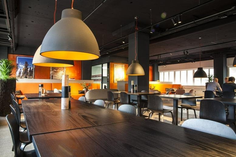 Spacious communal lounge at Raamplein 1 with large dome pendant lights and a warm orange feature wall.