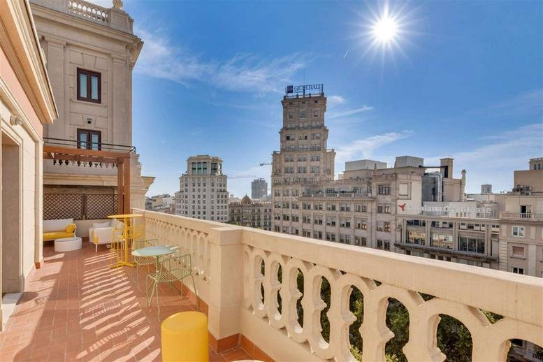 Sunny rooftop terrace at Rambla de Catalunya, 18, Barcelona with city views and lounge seating.