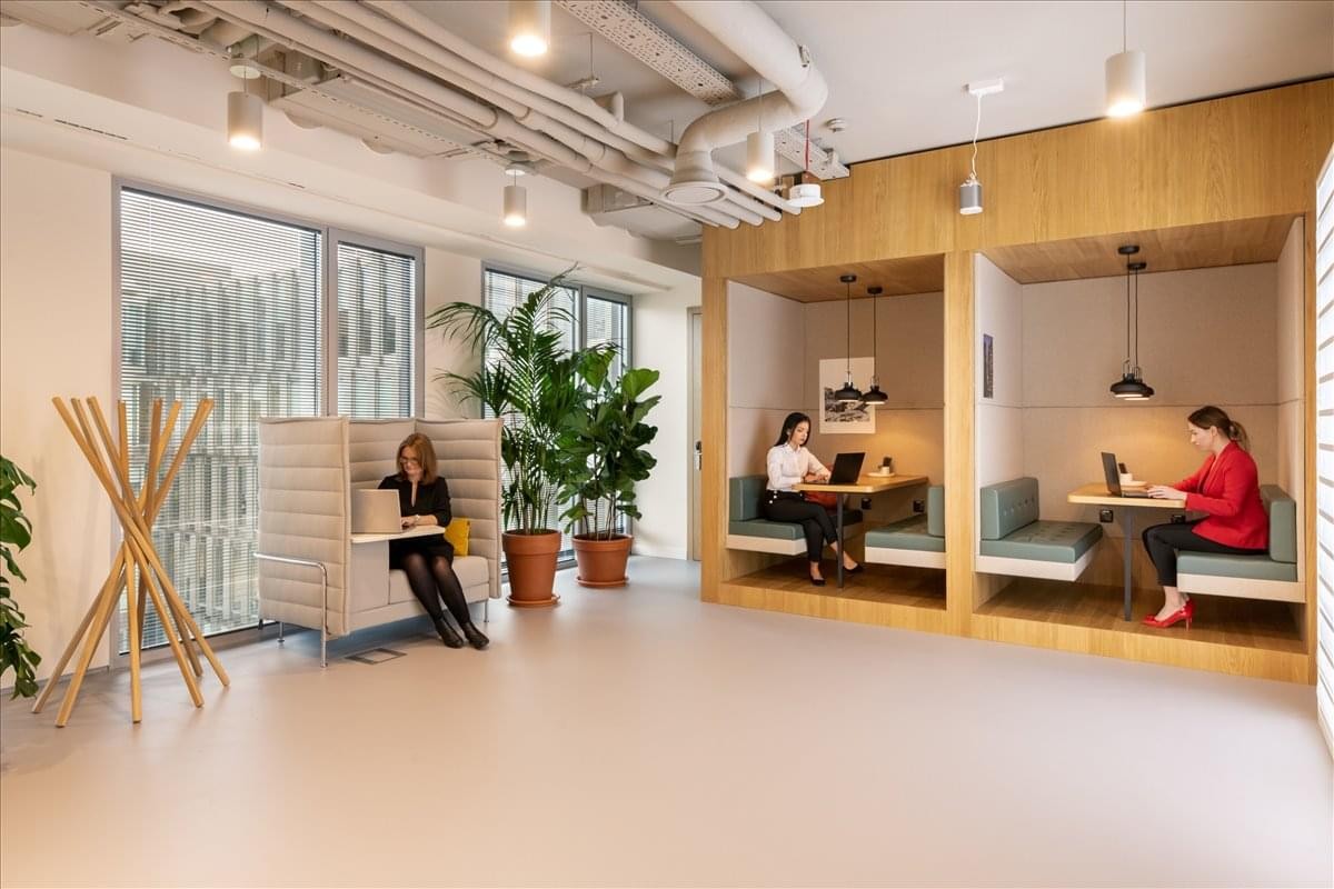 Spacious communal breakout area at Rayskistraße 25 with wooden focus booths and indoor plants.