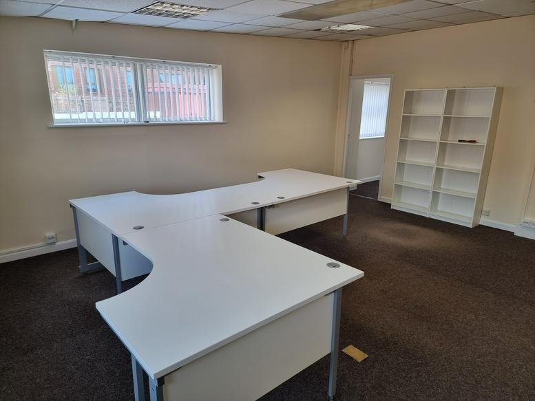 Spacious office suite featuring a large white L-shaped desk and built-in white shelving.