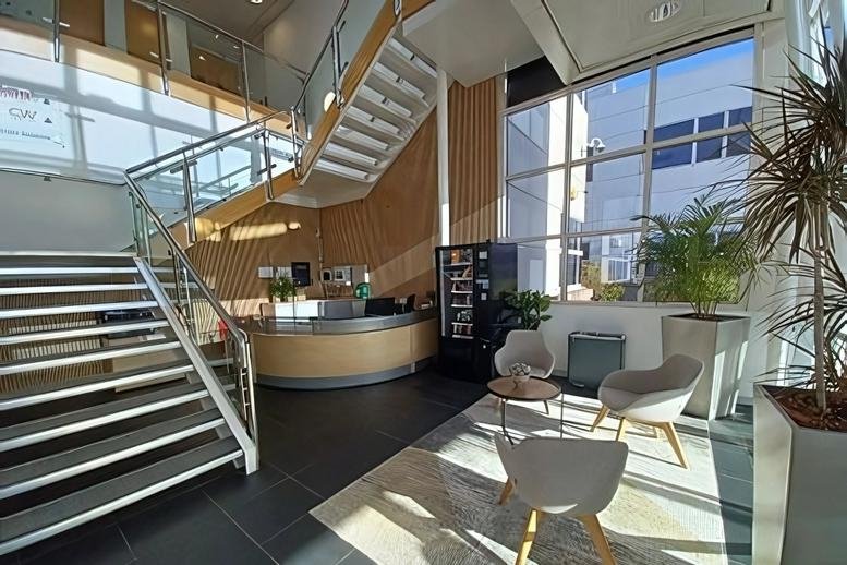 Spacious, modern lobby at Richmond House, Oldbury featuring a sweeping staircase, wooden reception desk, and lounge area.