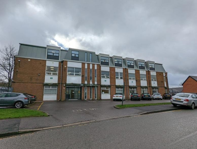 Exterior view of the brick-built Rico House with a grey mansard roof and onsite parking.