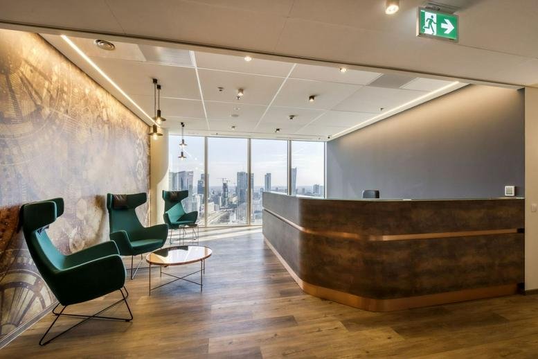 Spacious reception area with green velvet armchairs and city views at Rondo Daszyńskiego 2b, Warsaw.