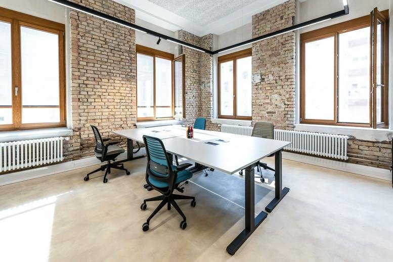 Spacious meeting room at Roonstraße 23a with exposed brick walls and large wooden windows.