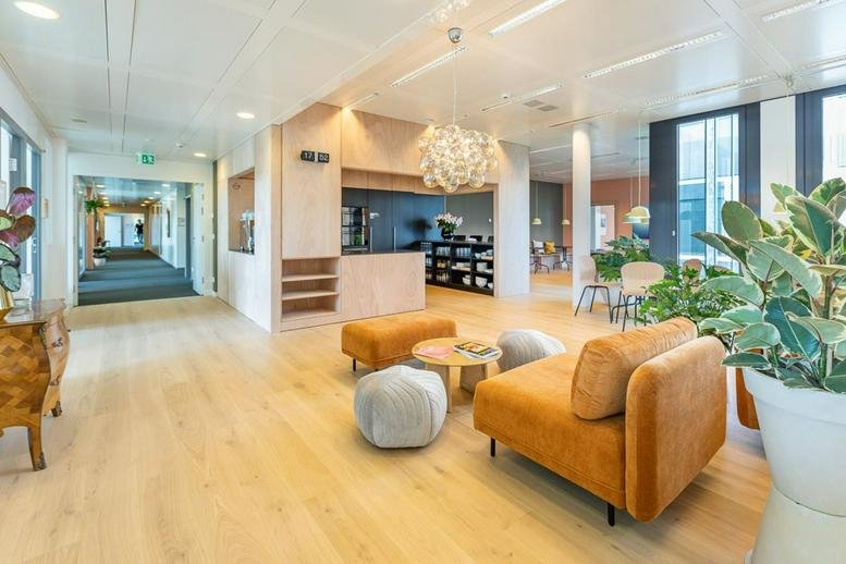 Spacious sunlit lounge at Route de Meyrin 123 with orange armchairs and a decorative pendant light.