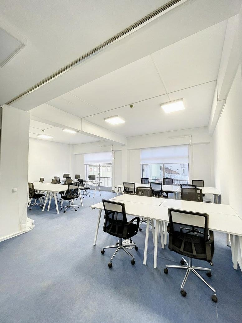 Bright office suite with multiple desks and blue carpeting.