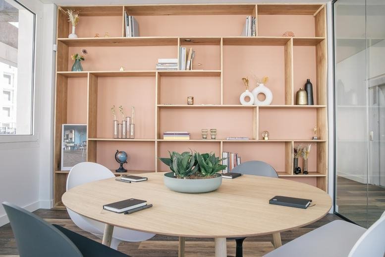 Spacious meeting room at Rua Engenheiro Fernando Vicente Mendes 7B featuring a wooden round table and light wood shelving.