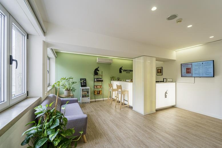 Bright reception at Rua Filipe Folque 2, 2nd floor, Lisbon with soft seating and a digital screen.