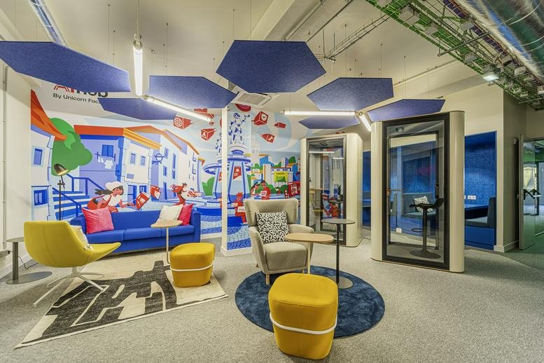 Vibrant lounge at Rua João Saraiva 34, 3, Lisboa featuring blue sofas, yellow ottomans, and colorful wall murals.