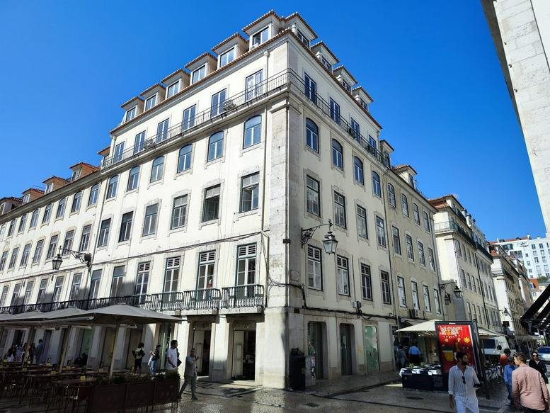 Grand historic stone building facade of Rua São Nicolau 73 - 1º under a clear blue sky.