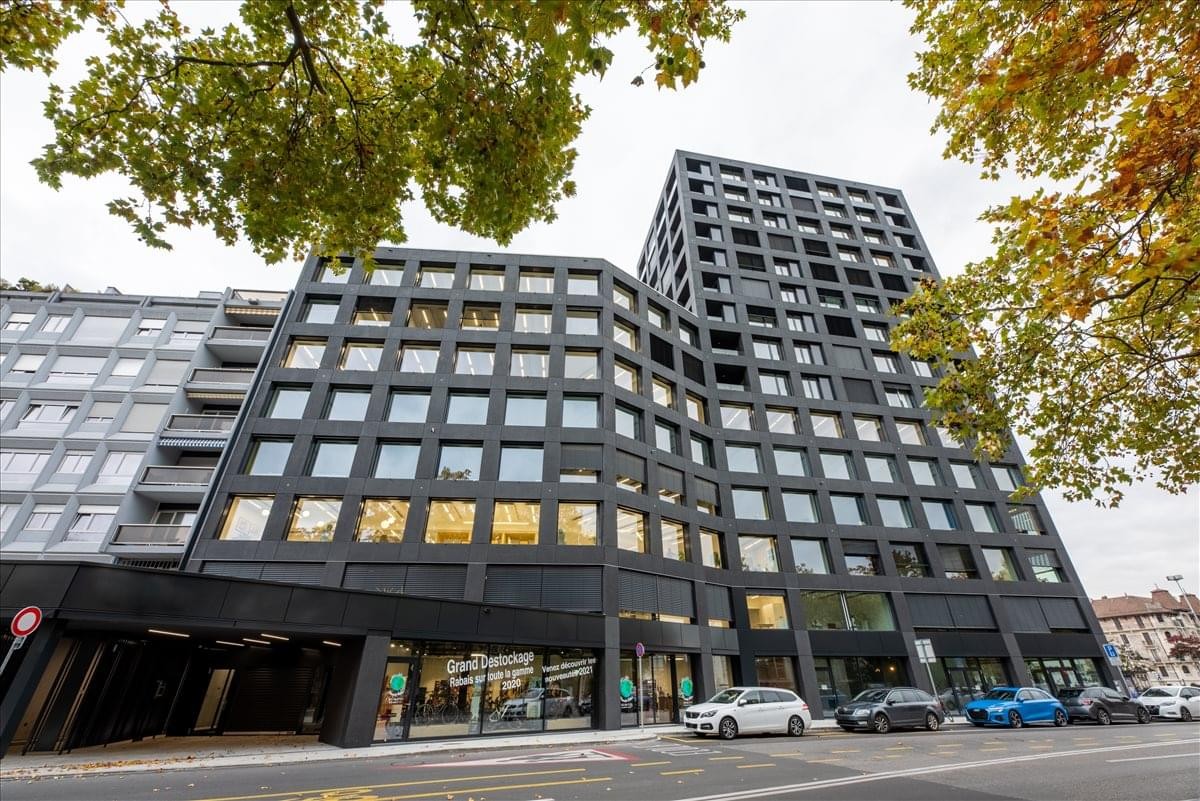 Exterior view of the modern black-facade building at Rue de Lyon 77, Geneva, Switzerland.
