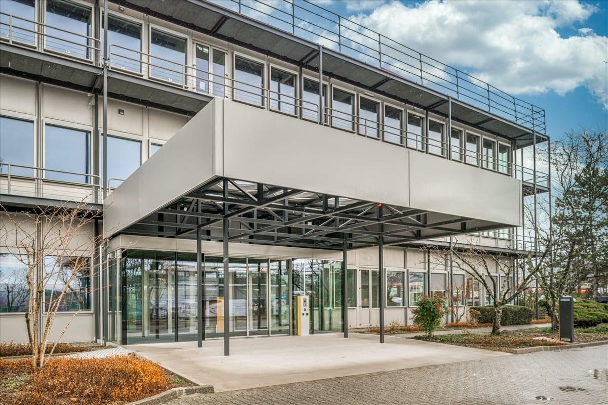 Modern exterior of the office building at Rue du Nant D'avril 150, Meyrin with a large covered entrance.