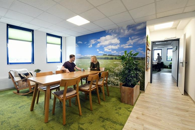 Bright coworking space at Südring 25, Bochum featuring a long wooden table and a scenic landscape wall mural.