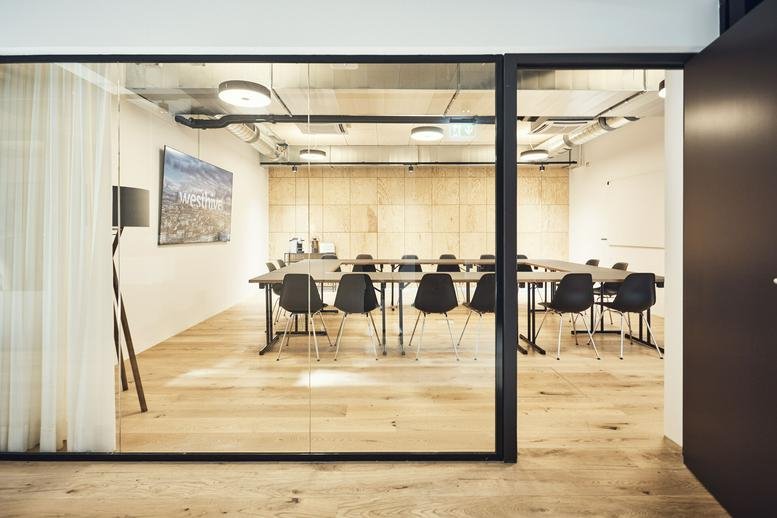 Spacious boardroom at Sandgrubenstrasse 44 with a large U-shaped table and glass partitions.