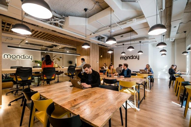Spacious coworking area at Santa Engracia 23 with long wooden tables and modern pendant lighting.