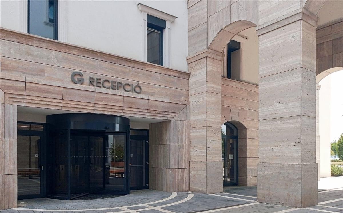 Exterior entrance of Sasbérc Utca 1, Topark, Biatorbagy with stone facade and revolving door.