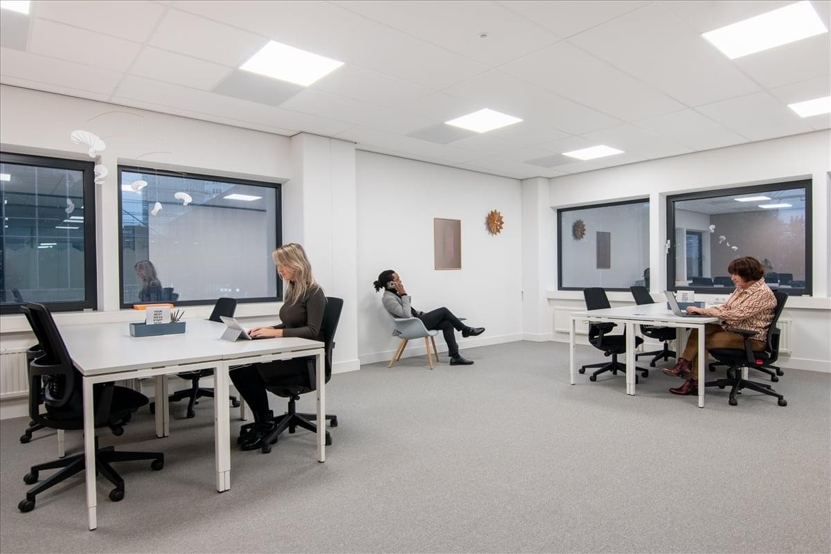 Spacious open-plan workspace at Schimmelt Eindhoven South Building with large windows and white desks.