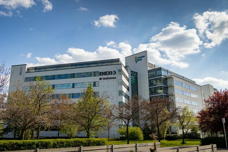 Exterior view of the white facade of the Science Park Business Center surrounded by trees.