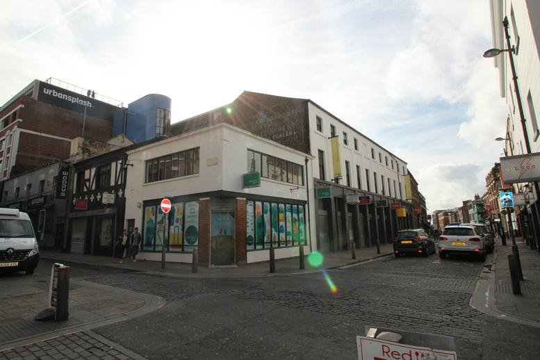 Wide-angle street view of the corner facade of Slater Studios under a bright sky.