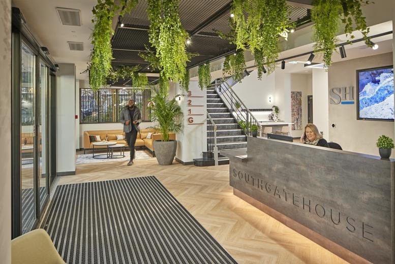 Modern reception desk with greenery-draped ceiling and comfortable lounge seating in the background.