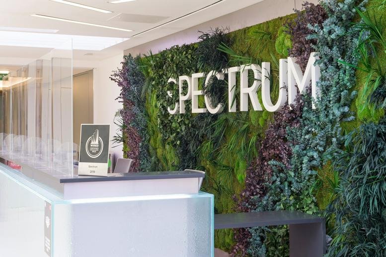 Vibrant reception area of Spectrum, Bond Street, Bristol featuring a lush green wall and white signage.