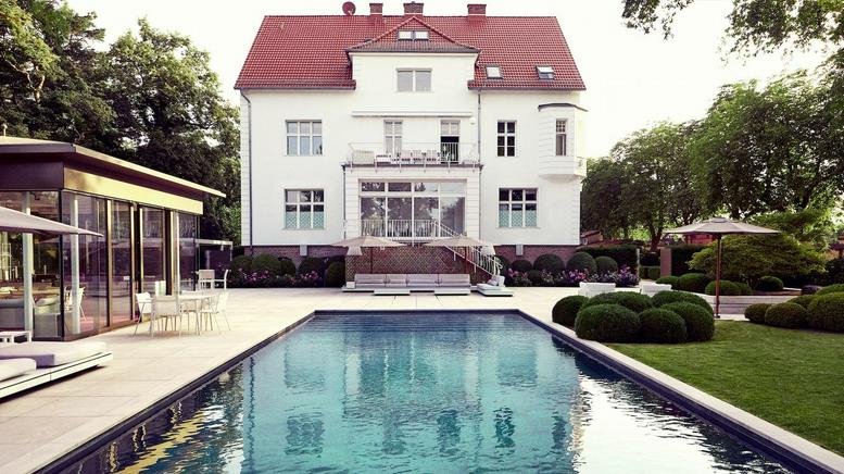 Exterior view of the stately white villa with a red roof at Spreetalallee 1.