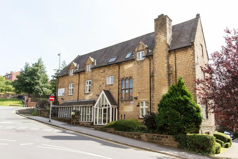 Stone exterior of St Andrew's House with gabled roof and large windows.