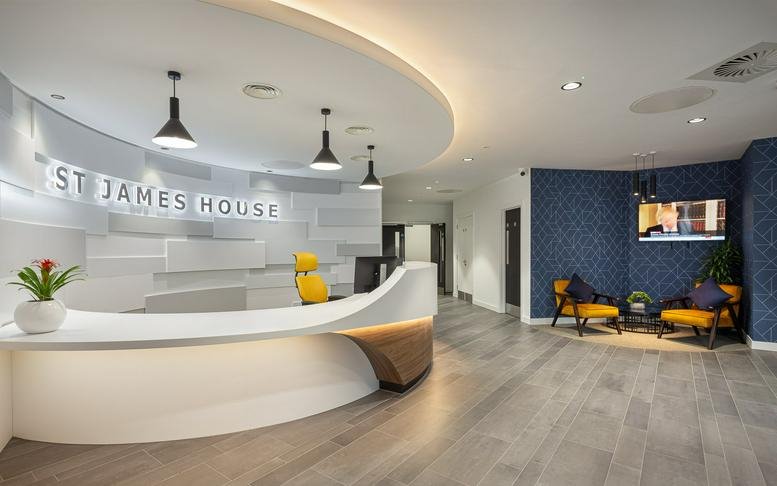 Bright, modern reception area at St James’ House with a curved white desk and warm wood accents.