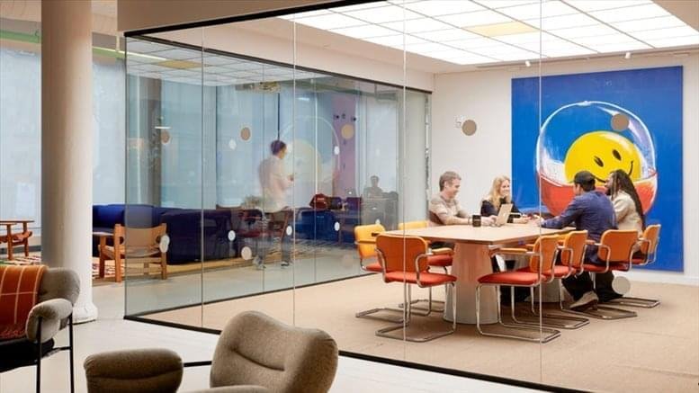 Spacious communal lounge at Stadhouderskade 5 with colorful furniture and a glass-enclosed meeting area.