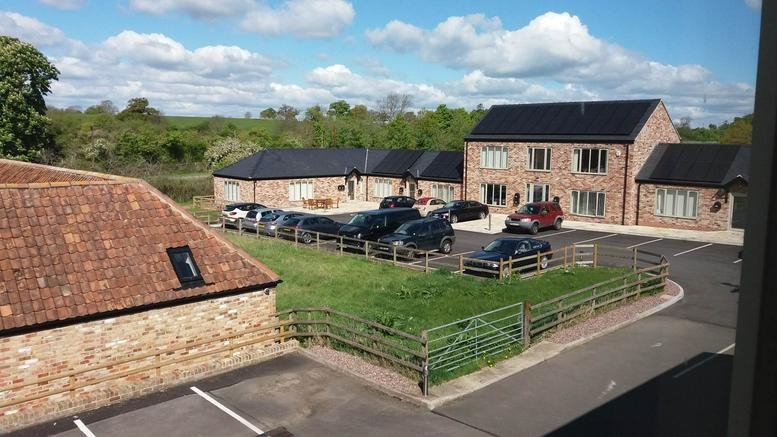 Exterior view of the brick buildings at Stonehouse, Stroud, Gloucestershire with a paved parking area.