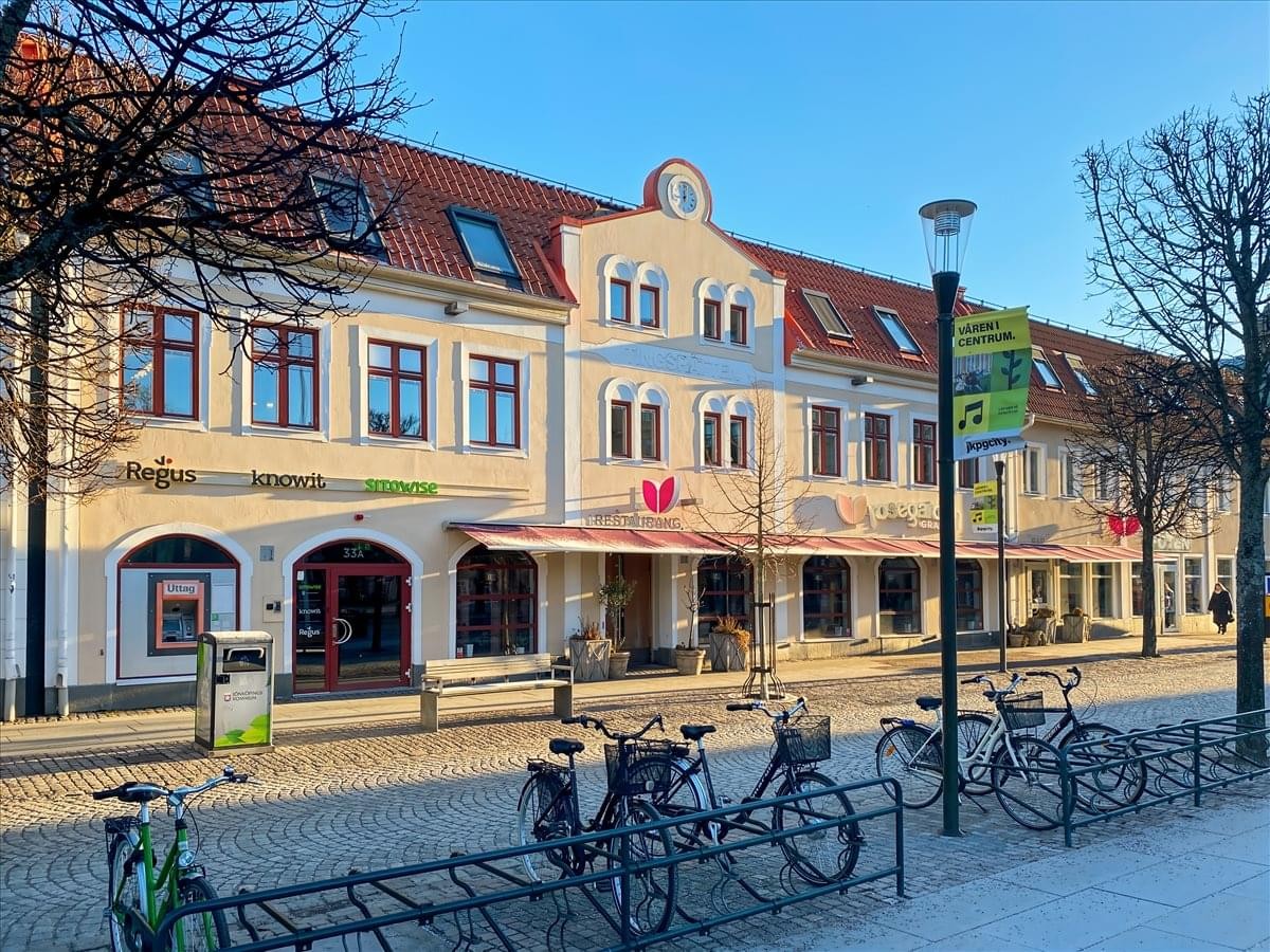 Exterior view of the historic building at Östra Storgatan 33A with storefronts and bicycle racks.