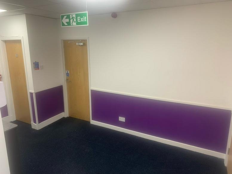 Entryway at Survey House Office/ The Store Room with purple accent walls and an exit sign.