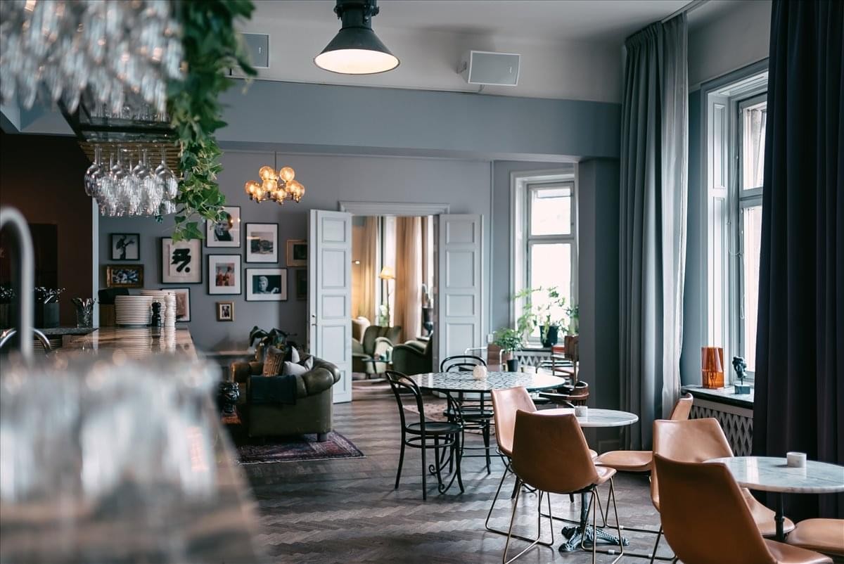 Spacious communal lounge at Sveavägen 50, Entréplan samt våning 1-5 with dining tables and greenery.