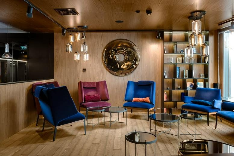 Colorful lounge area at Szczytnicka 11 Street with velvet armchairs and wood paneling.