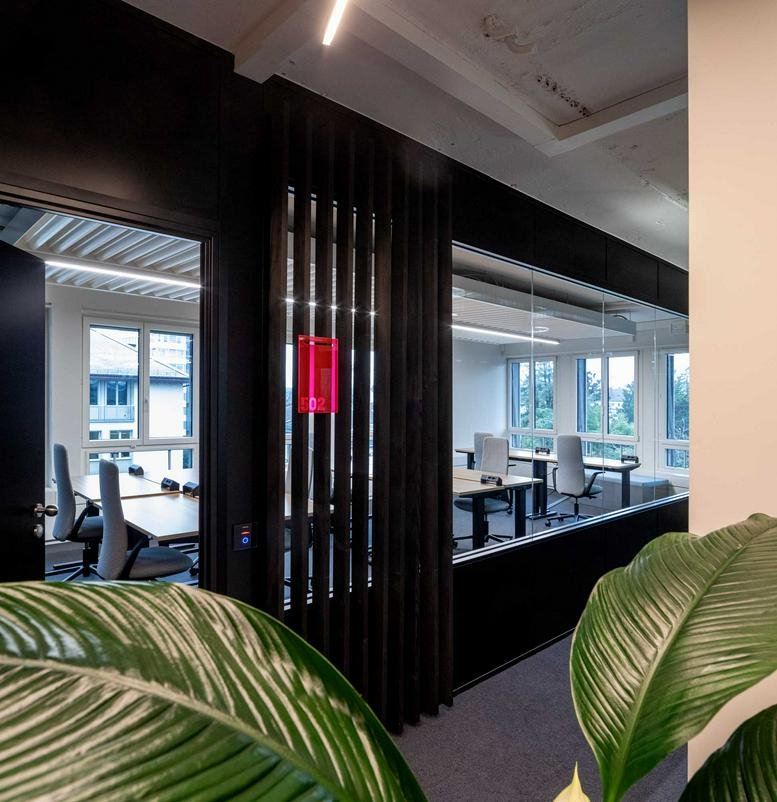 Spacious open-plan workspace at Talacker 41, Zurich, Switzerland with dark wood partitions and natural light.