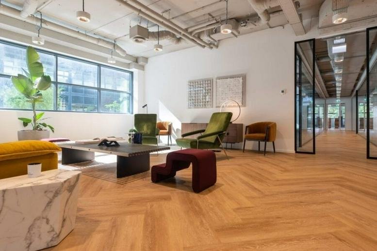 Spacious communal lounge at Teleportboulevard 130 featuring mid-century modern furniture and herringbone wood floors.
